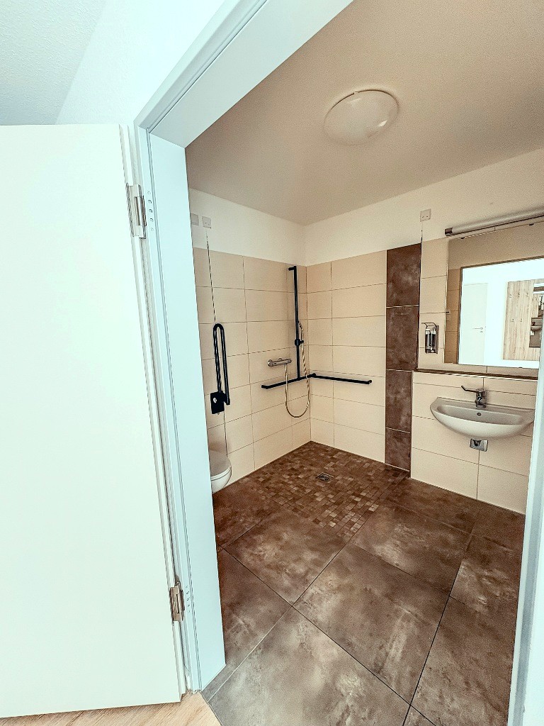 Bodengleiche, schwellenlose Dusche mit stabilen Sicherheits-Haltegriffen im barrierefreien Badezimmer