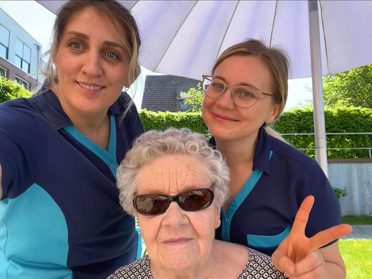 Mitarbeiterinnen im Austausch mit einer Bewohnerin im grünen Garten