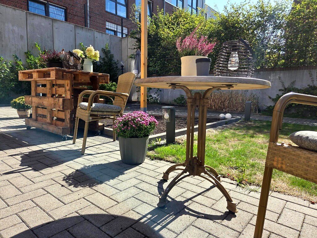 Sonnige Gartenterrasse mit gemütlichem Sitzbereich und grüner Parkanlage im Seniorenhaus Lohne