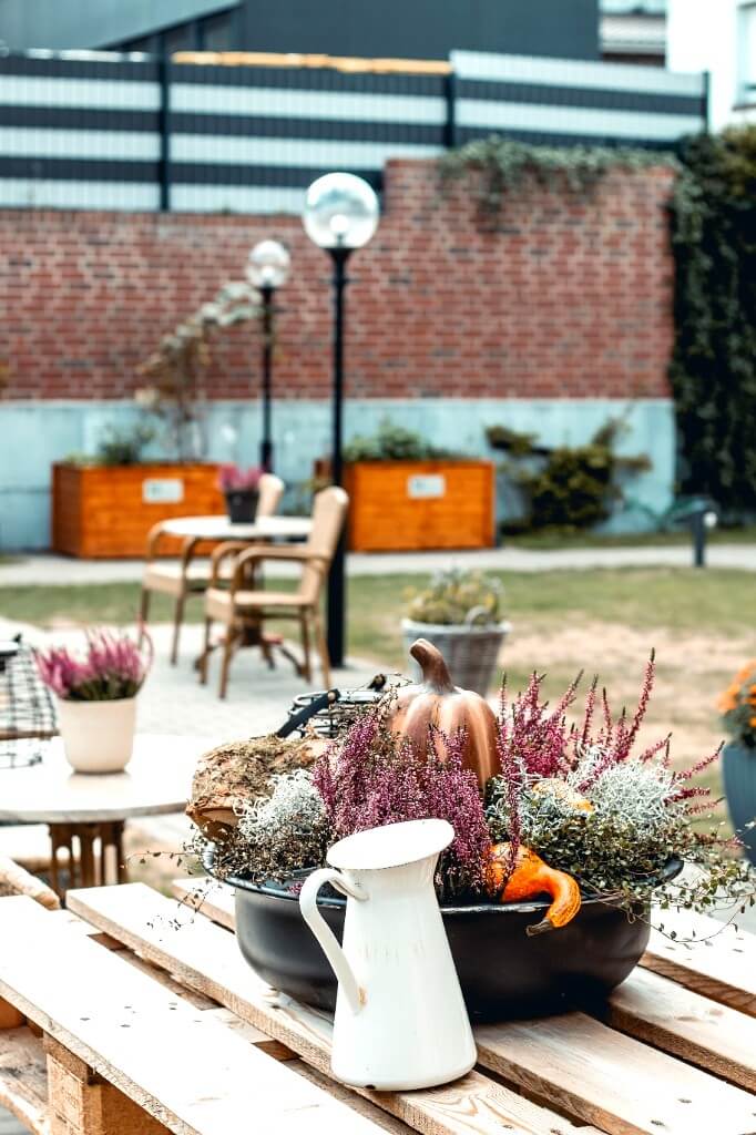 Saisonale Herbstdekoration mit Zierkürbissen und Heidekraut im Eingangsbereich und Garten