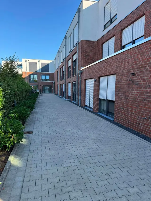 Gepflasterter, ebenerdiger Spazierweg im Außenbereich des Altenheims Lohne