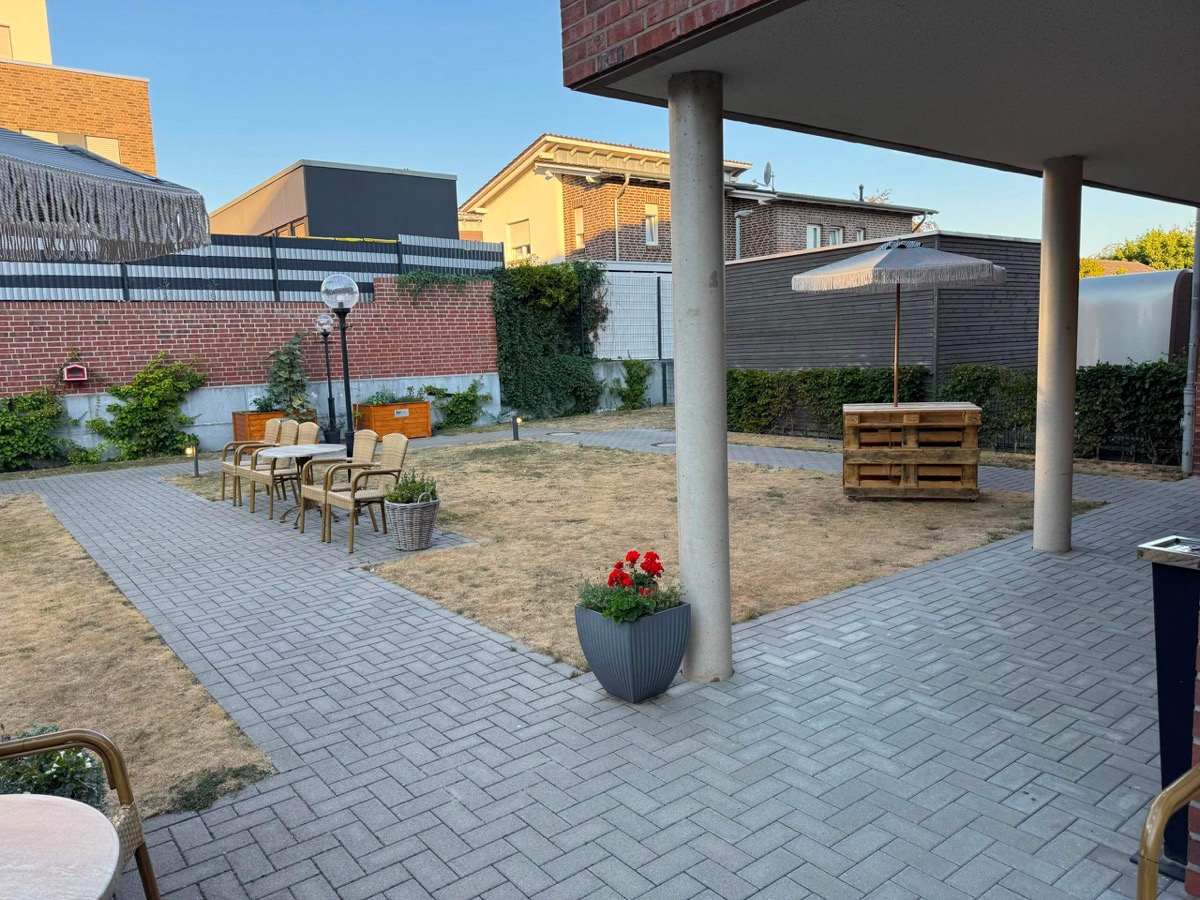 Sonnige Außenterrasse mit gemütlicher Palettenbar im Garten des Seniorenheims